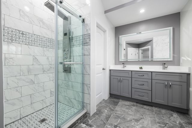 Renovated bathroom in a Kitchener home with walk-in glass shower, quartz vanity and large-format porcelain tile